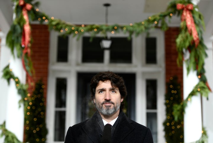 Festive garlands hang from the pillars of Rideau Cottage as Prime Minister Justin Trudeau speaks during a news conference on Dec. 23, 2020.