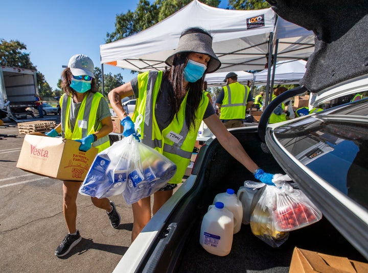 Volunteer Anh Tonnu (left) and sister Tomi Tonnu load a car in Fountain Valley, California, with food on Oct. 14 as part of Saddleback Church's drive-thru food distributions to families in need.