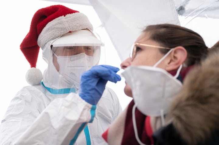 Una trabajadora sanitaria con un gorro de Papá Noel practica una PCR