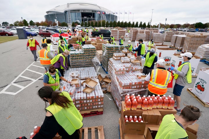 Volunteers build bags of dry goods in a parking lot outside of AT&T Stadium during a Tarrant Area Food Bank mobile pantry dis