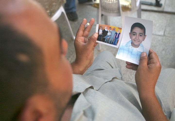 Mohammed Hafiz looks at photos of his 10-year-old son in Baghdad on Oct. 4, 2007. The boy died after the attack on Iraqi civi