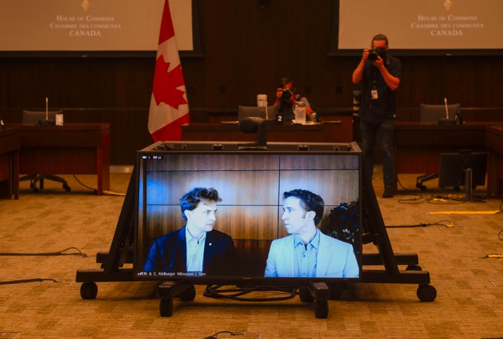 Marc Kielburger, screen left, and Craig Kielburger, screen right, appear as witnesses via videoconference during a House of Commons finance committee in the Wellington Building in Ottawa on July 28, 2020.