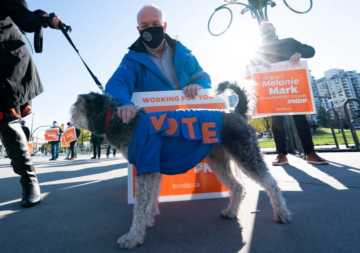 NDP Leader John Horgan stops to pet candidate Melanie Mark's dog Max as he greets supporters on election day in Vancouver on Oct. 24, 2020.