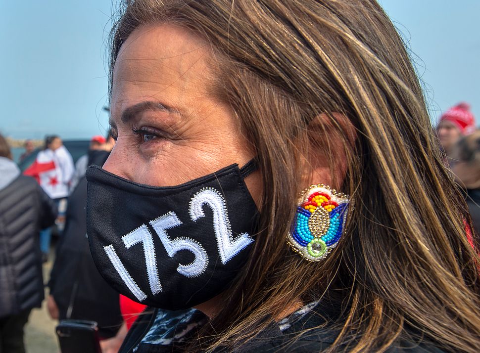 A woman wears a face mask honouring the Treaty of 1752 as members of the Sipekne'katik First Nation and others attend a ceremony on the wharf in Saulnierville, N.S., to bless the fleet before it launches its own self-regulated fishery on Sept. 17, 2020.