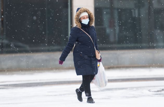 A woman wears a face mask as she crosses a street on Boxing Day in Montreal on