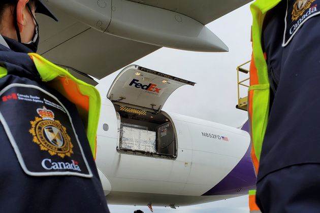 Canada Border Services Agency officers watch as the first shipment of Moderna's COVID-19 vaccine arrives...