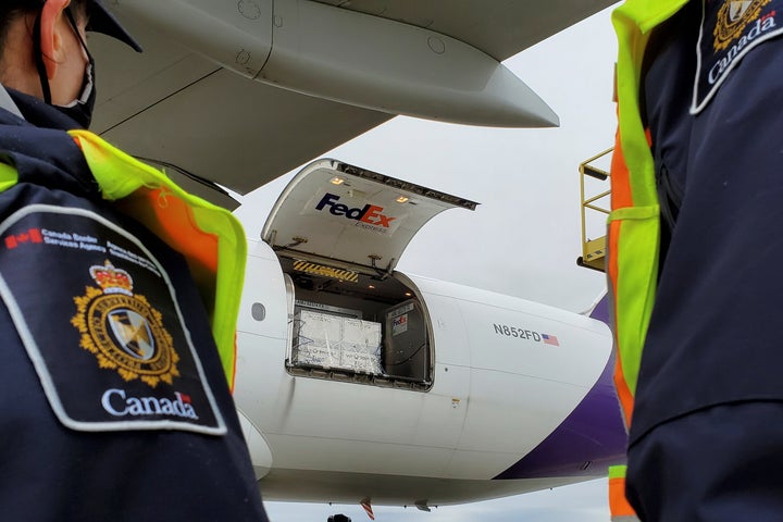 Canada Border Services Agency officers watch as the first shipment of Moderna's COVID-19 vaccine arrives in Canada on Dec. 24, 2020.