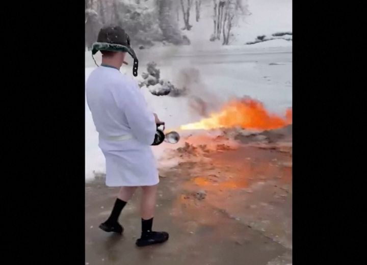 火炎放射器で除雪する男性