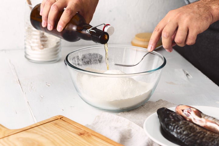 Un hombre preparando una receta de pescado rebozado con cerveza. 