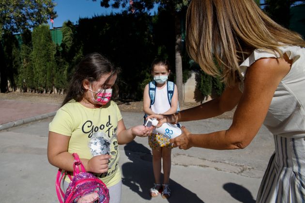 Una profesora pone gel en las manos a una niña en el primer día de colegio, en un centro...