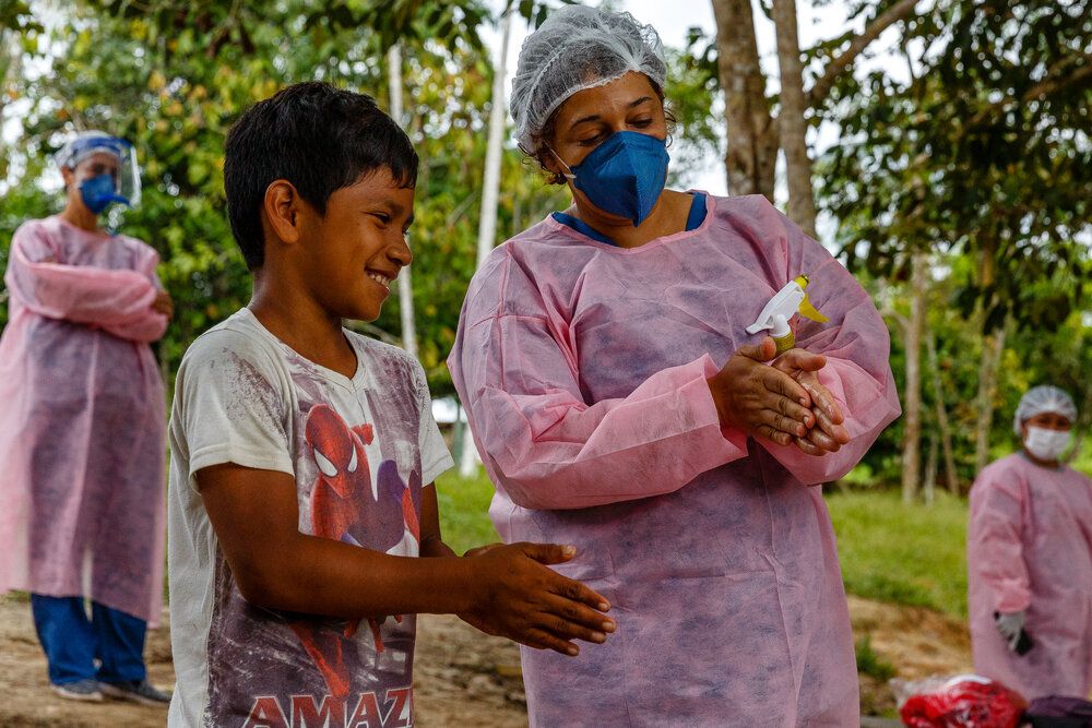 Η νοσηλεύτρια Νάρα Ντουάρτε στη Βραζιλία δείχνει σε αυτό το αγόρι πώς να πλένει και να απολυμαίνει σωστά τα χέρια του εν μέσω της πανδημίας COVID-19. Τα ελάχιστα διαγνωστικά τεστ που διέθεσαν οι αρχές της χώρας, σε συνδυασμό με τις απομονωμένες και δυσπρόσιτες κοινότητες και τις δυσκολίες στις μετακινήσεις, οδήγησαν σε ένα μεγάλο αριθμό νεκρών και σοβαρά ασθενών από τον κορονοϊό.
