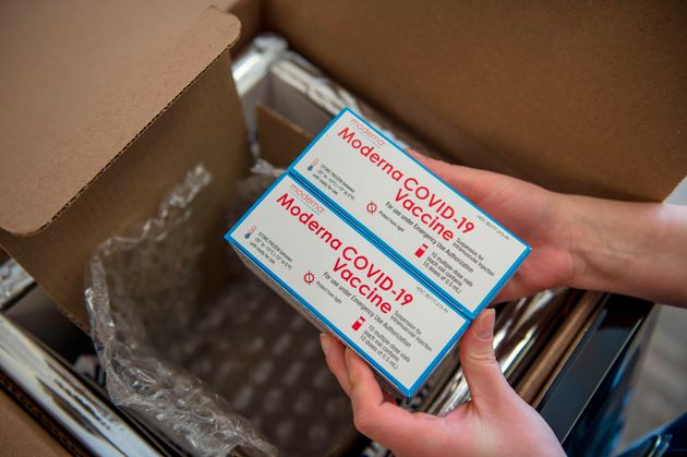 A regisered nurse unpacks a special refrigerated box of Moderna COVID-19 vaccines as she prepares to...