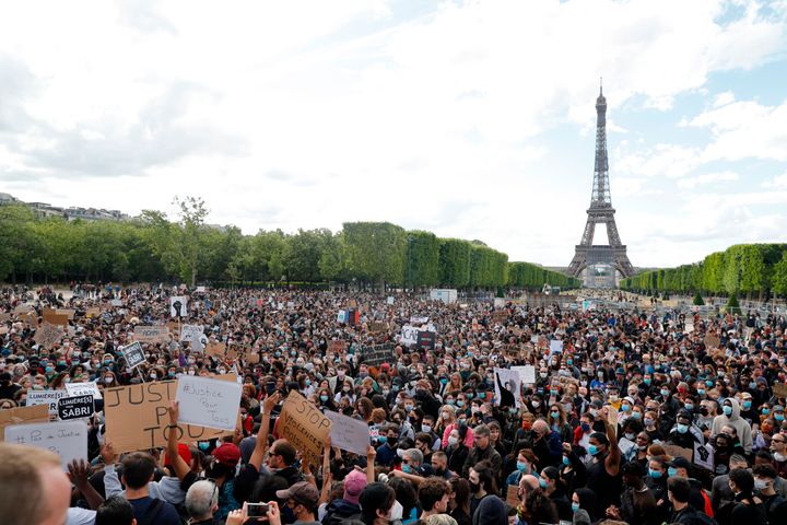 A protester holds a banner on Champ de Mars, in Paris, on June 6, 2020, as part of worldwide protests against racism and police brutality in the wake of the death of George Floyd, an unarmed black man killed by police in Minneapolis.