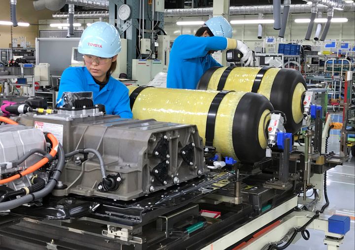 Workers at Toyota Motor Corp. set hydrogen-stored tanks, in yellow, to be placed into a fuel cell vehicle in Toyota, Japan on Oct. 30, 2017. Toyota is banking on hydrogen fuel cells for its zero-emissions vehicle option.