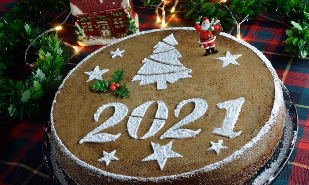 Concept with traditional Greek new years cake,vasilopita, decorative with a mistletoe and a saint claus, red tassels,artificial pine and red berries sticks around