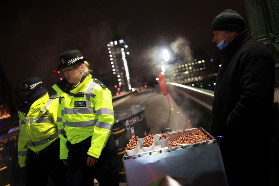 Police officers walk past a street vendor selling nuts on Westminster Bridge.