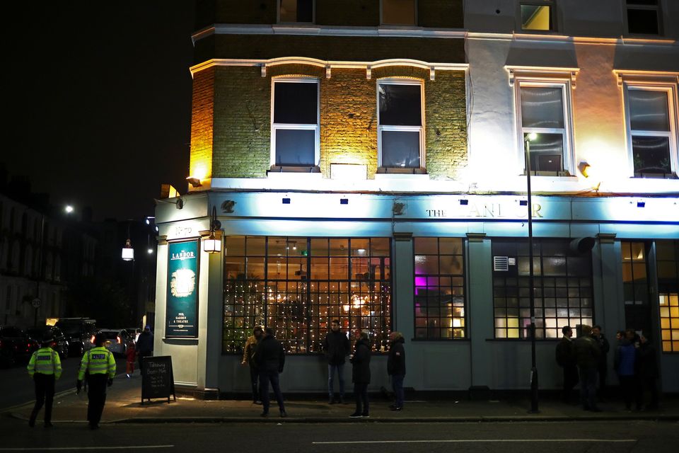 People stand outside a pub that is open for takeaway drinks on New Year's Eve in London.