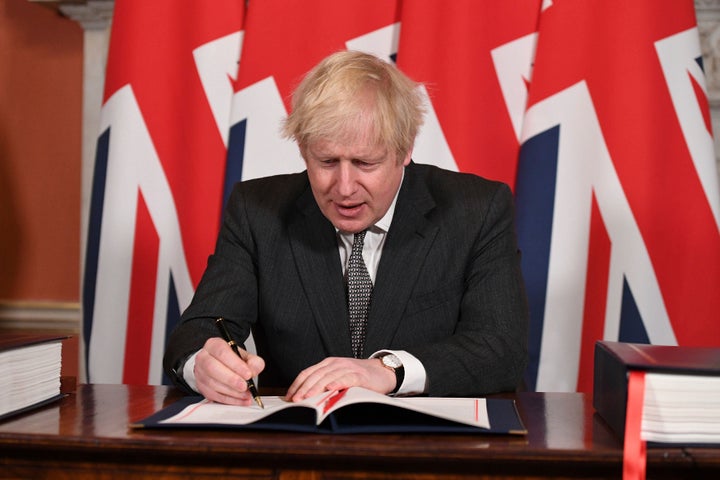 Britain's Prime Minister Boris Johnson signs the EU-UK Trade and Cooperation Agreement at 10 Downing Street, London Wednesday Dec. 30, 2020. (Leon Neal/Pool via AP)