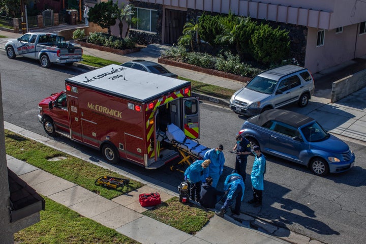 Los Angeles County paramedics examine a potential Covid-19 patient sitting on the sidewalk before transporting him to a hospital in Hawthorne on Tuesday.