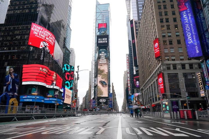 Pedestrians walk in a nearly empty Times Square ahead of the New Year's Eve celebration Thursday, Dec. 31, 2020, in New York.