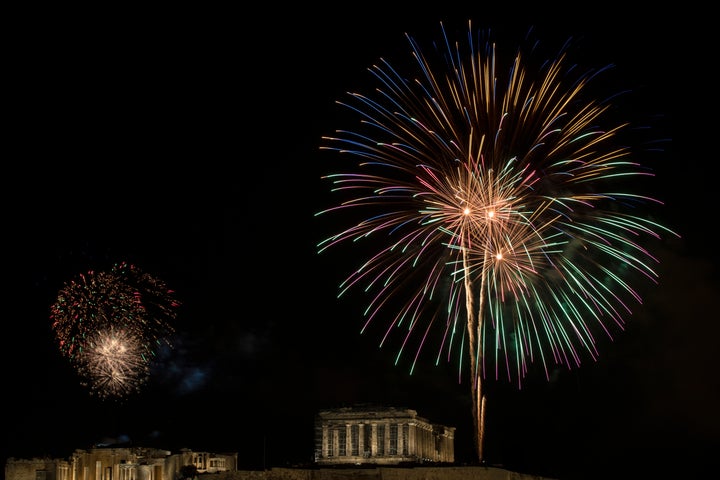 Fireworks explode over the ancient Acropolis hill with the Parthenon temple on the right and the Propylea on the left during 