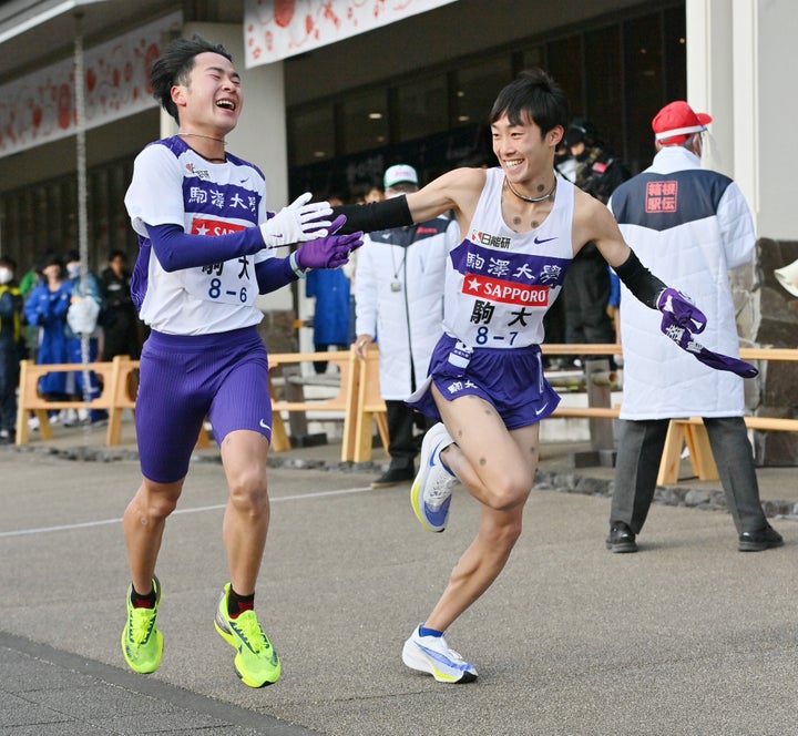 小田原中継所で6区の花崎悠紀（左）からたすきを引き継ぐ駒大7区の花尾恭輔＝1月3日、神奈川県小田原市