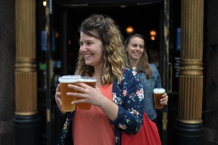 Customers leave with pints of beer for takeaway at The Ten Bells pub in east London on June 27, 2020. 