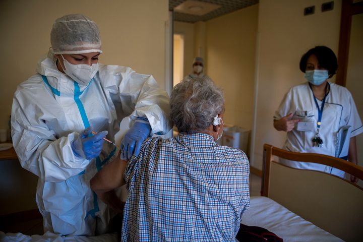A healthcare worker gives the Pfizer-BioNTech Covid-19 vaccine to nursing home resident in Rome on January 4, 2021 in Rome.