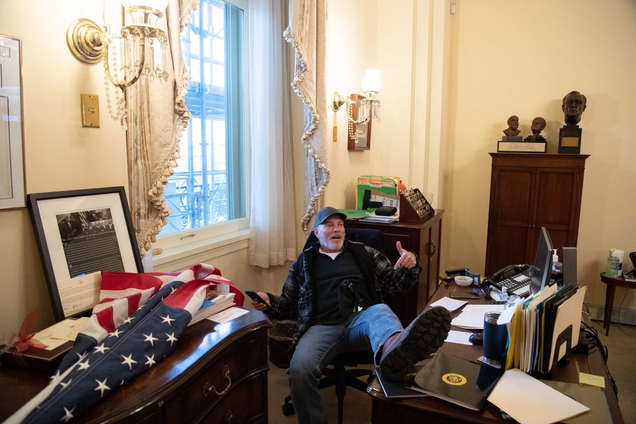 A pro-Trump rioter puts his feet up in Speaker Nancy Pelosi's offices. The desk reportedly belongs to her assistant.