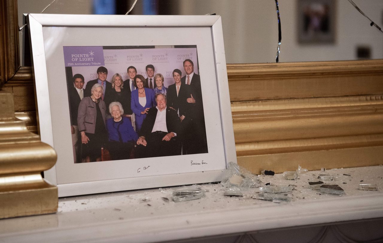Broken glass litters a mantle in Pelosi's offices before a photo of the speaker and the late President George H.W. Bush.