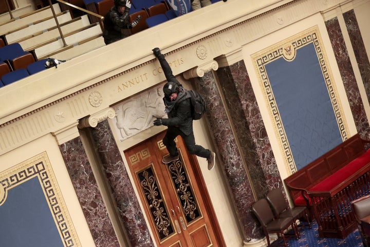 A pro-Trump protester hangs from the balcony in the Senate Chamber. 