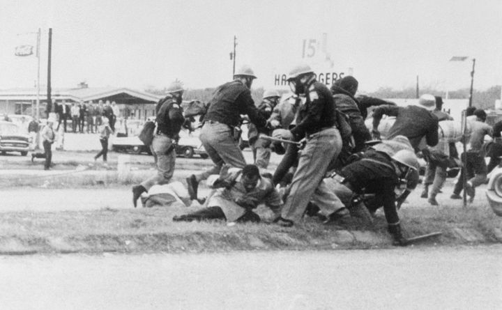 John Lewis (center, in the light coat) attempts to ward off a blow from a state trooper as civil rights activists marched from Selma to Montgomery, Alabama, on March 7, 1965. Lewis was later admitted to a local hospital; he had a fractured skull. 