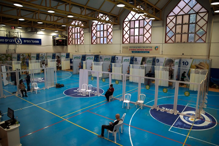 Israelis wait to receive coronavirus vaccine at a COVID-19 vaccination center, set up on a basketball court in Hod Hasharon, 