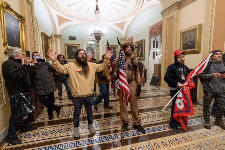 Supporters of President Donald Trump confront U.S. Capitol Police outside the Senate Chamber in the Capitol. At center is Jake Angeli, a regular at pro-Trump events and a known follower of QAnon. 