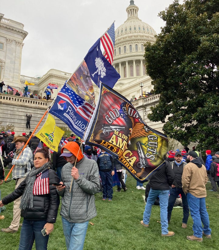 People hold flags glorifying violence and religion near the U.S. Capitol, which was breached on Jan. 6 by thousands of rioter