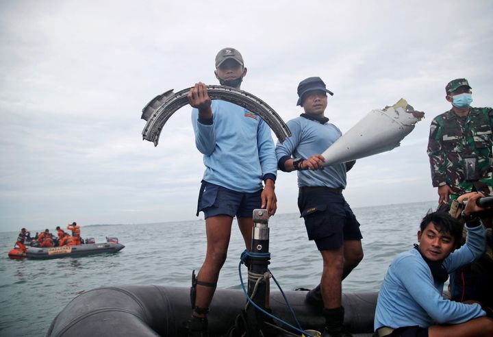 Indonesian Navy divers show parts of an aircraft recovered from the water during a search operation for the Sriwijaya Air passenger jet.