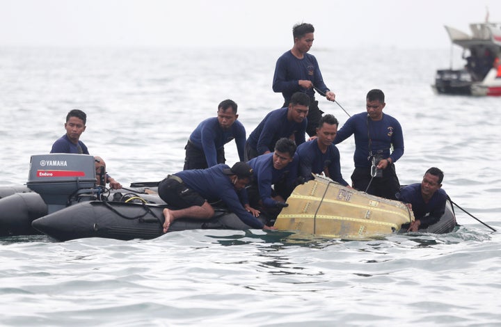 Indonesian Navy divers pull out a part of an airplane out of the water during a search operation for the Sriwijaya Air passen