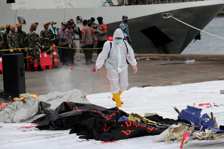 A workers sprays disinfectant on body bags containing the remains of passengers of Sriwijaya Air Flight 182 that crashed in t