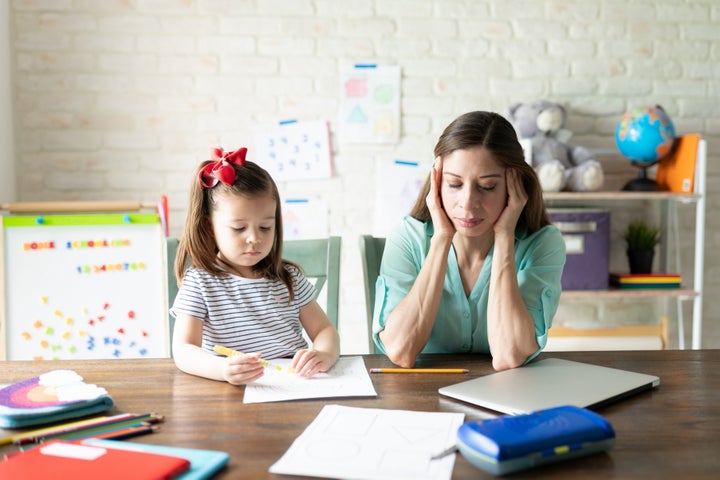 A stock photo of a mother with child during attempting to help with online school.
