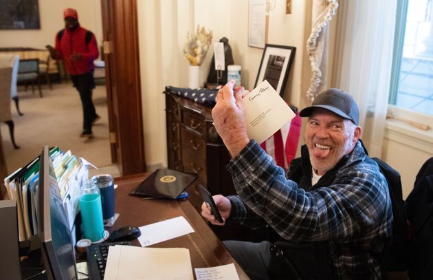 Trump supporter Richard Barnett holds a piece of mail as he sits inside the office of House Speaker Nancy Pelosi after protesters breached the U.S. Capitol on Jan. 6, 2021. 