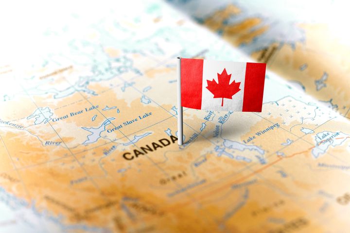 A map of Canada with a flag pinned to it. 