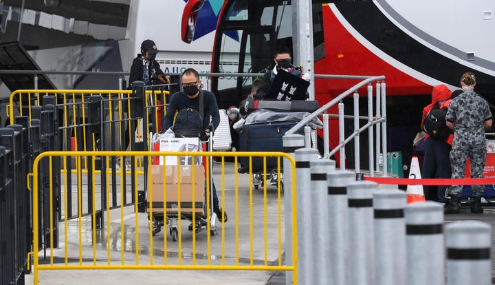 Passengers wearing face masks and face shields having recently landed from overseas walk to a hotel quarantine bus at Sydney International Airport on January 08, 2021 in Sydney, Australia. 