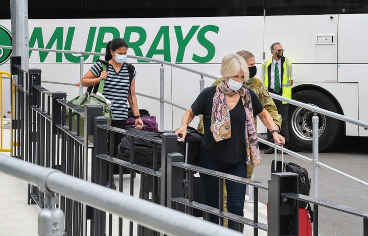 Passengers wearing face masks and face shields having recently landed from overseas walk to a hotel quarantine bus at Sydney International Airport on January 08, 2021 in Sydney, Australia. T