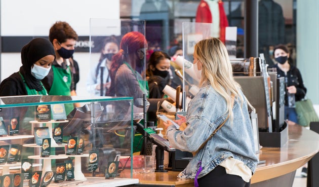 A customer wearing a face mask buys coffee at a Starbucks cafe in Toronto, Sept. 14, 2020. Starbucks says its plan to close up to 300 coffee shops across Canada will be complete by the end of March.