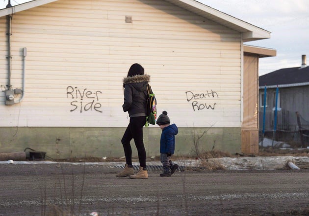 A woman and a child walk through the streets in Attawapiskat, Ont., on April 16, 2016.