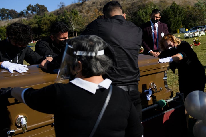 Family members mourn over the casket of Gilberto Arreguin Camacho, 58, who died from COVID-19, at a cemetery in Whittier, Cal