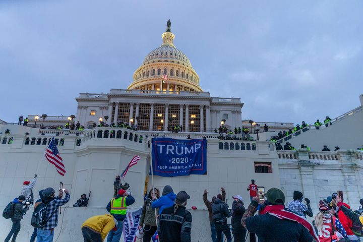 Insurrectionists hang Trump 2020 flags on the Capitol as they run rampant the building.