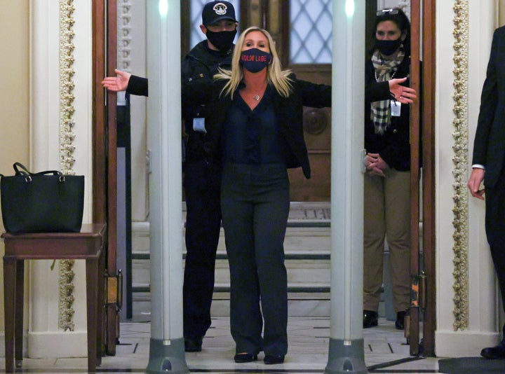 Rep. Marjorie Taylor Greene (R-Ga), a QAnon conspiracy theorist, is searched outside the House chamber Tuesday night. Her mask says <em>molon labe</em>, a Greek phrase meaning “come and take them” that the right wing uses as an anti-gun control slogan.
