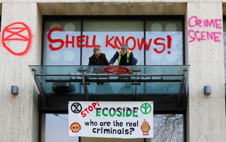 A climate activist sprays graffiti on the entrance to the Shell's British offices.