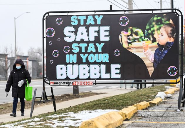 A woman walks past a COVID-19 messaging sign during the COVID-19 pandemic in Mississauga, Ontario on...